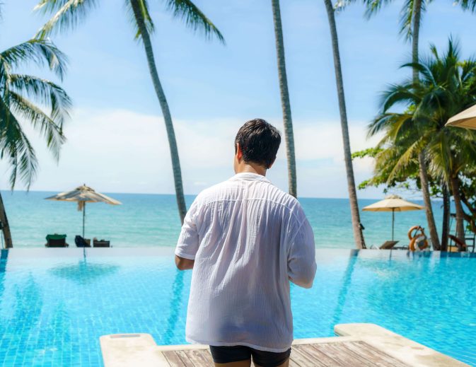 hombre-asiatico-camina-quita-camisa-blanca-prepararse-saltar-piscina-mientras-descansaba-vacaciones-verano